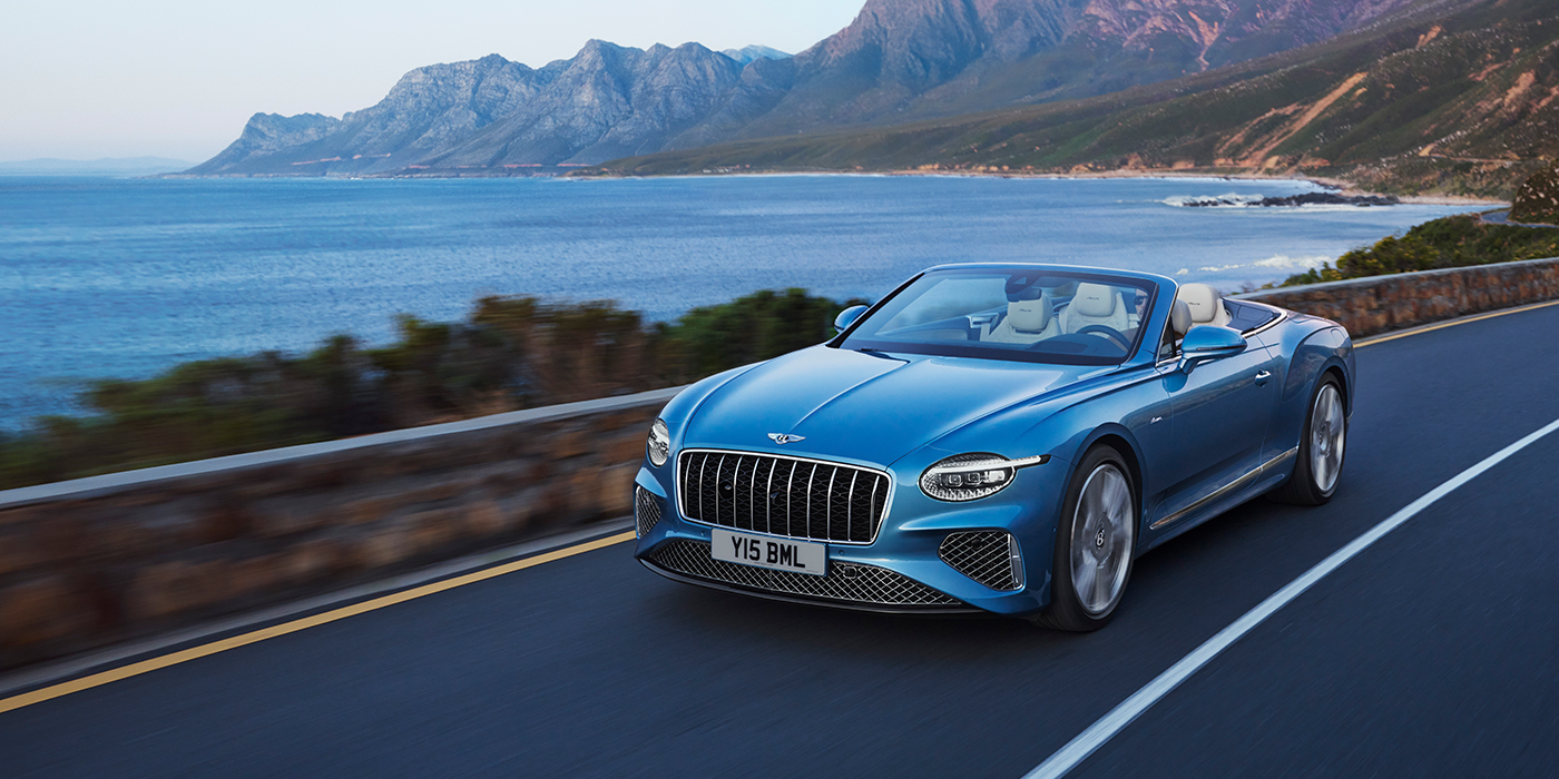 Bentley Paris Seine New Bentley Continental GTC Azure convertible in Light Windsor blue paint with 22 inch Azure wheels and chrome grill, driving dynamically by the sea