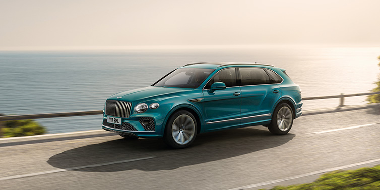 Bentley Paris Seine Bentley Bentayga Extended Wheelbase Azure SUV in Topaz blue paint driving dynamically by the ocean