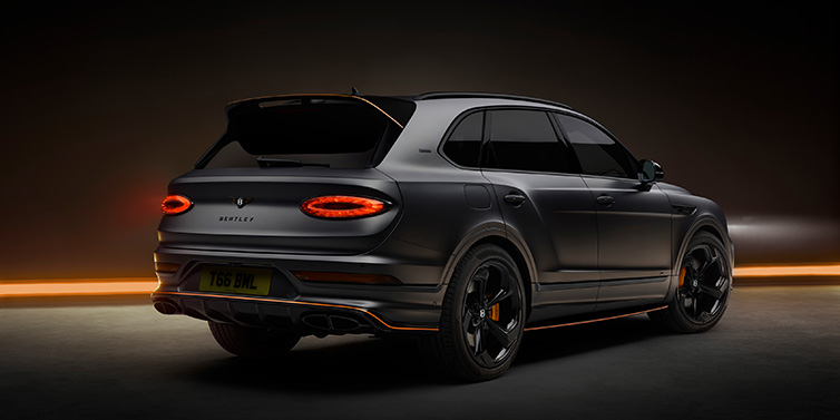 Bentley Paris Seine Bentley Bentayga S Black Edition SUV rear three quarter in Anthracite Satin paint against a dark red and yellow background