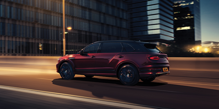 Bentley Paris Seine Bentley Bentayga Extended Wheelbase Mulliner SUV in Cricket Ball red paint driving dynamically in city at night