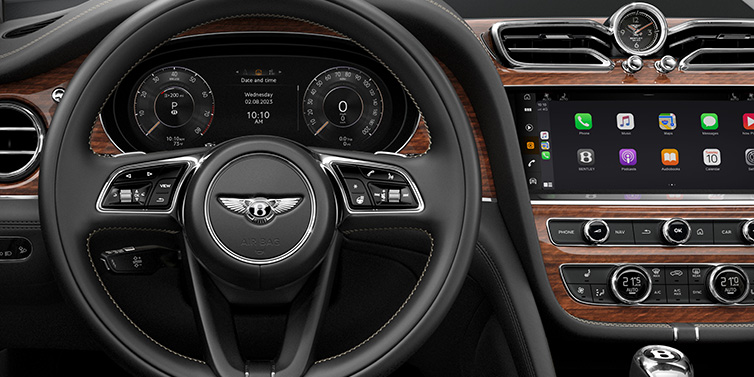 Bentley Paris Seine Bentley Bentayga SUV front interior detail of steering wheel and driver screens surrounded by Beluga black hide and Crown Cut Walnut veneer